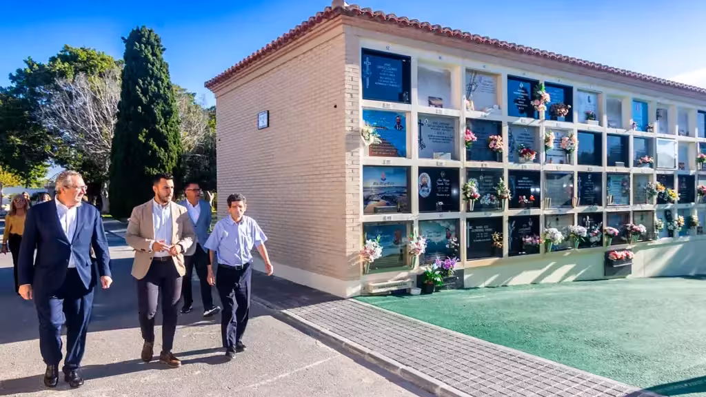 Un grupo camina junto a filas de nichos en un cementerio municipal de Benidorm