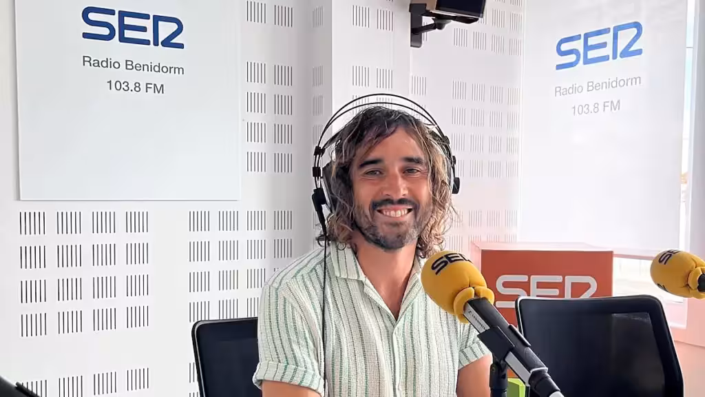 A man wearing headphones beside a microphone in a Radio Benidorm studio