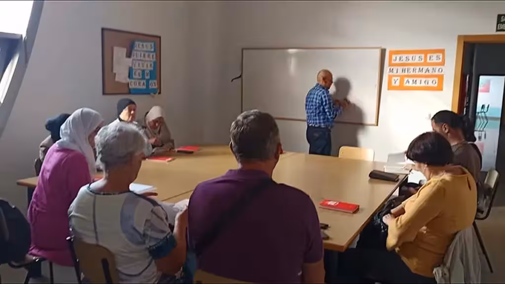 Participantes de una clase reunidos en torno a una mesa con material de estudio