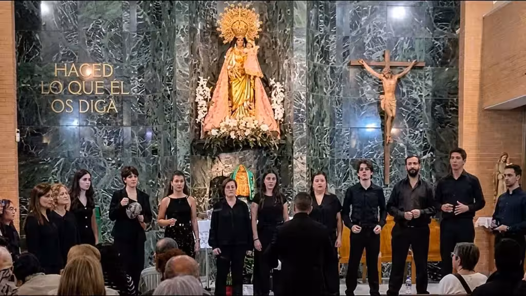El Coro Maestro Casanovas cierra en Elche los Encuentros Corales con otras tres agrupaciones Conjunto vocal vestido de negro ante un director en un interior religioso, con público en primer término; imagen ilustrativa.