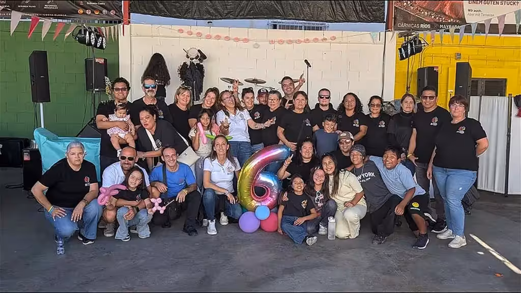 Participants at the Donaciones Torrevieja anniversary beside a balloon shaped as the number six