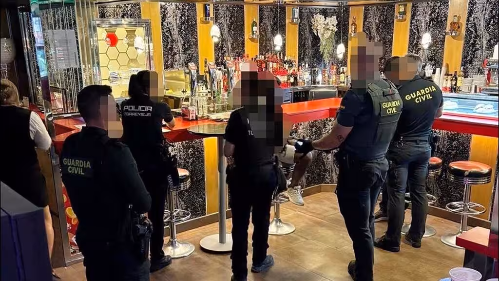 Agentes de la Policía Local y la Guardia Civil en el interior de un establecimiento de ocio, con los rostros pixelados en la imagen original