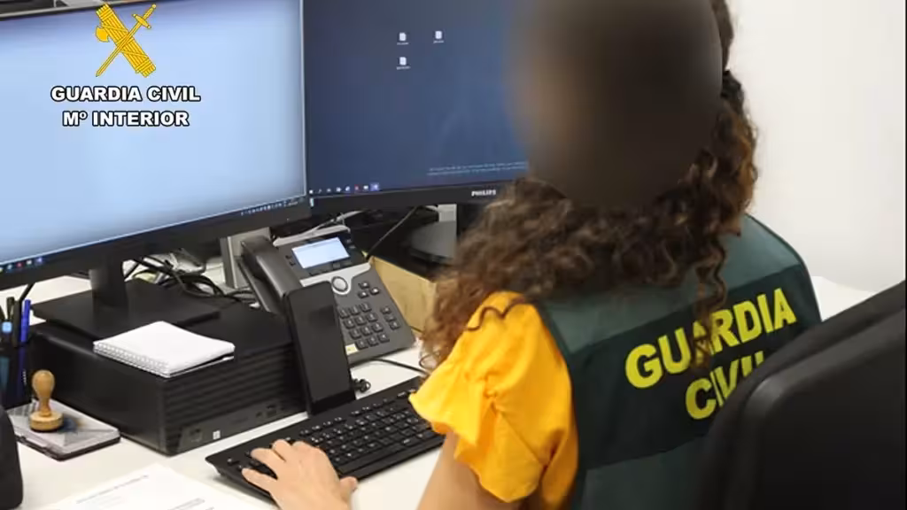 Persona con chaleco de la Guardia Civil ante dos pantallas, con el rostro difuminado