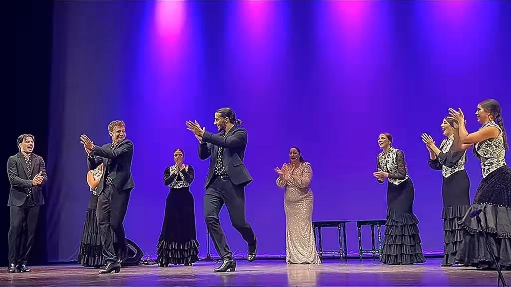 Artistas de flamenco sobre el escenario bajo una iluminación violeta