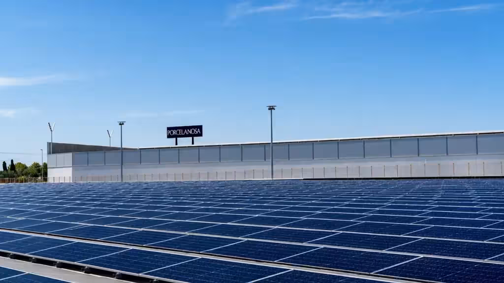 Solar panels beside an industrial building, shown in a general illustrative photograph.