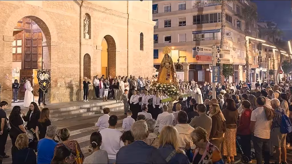 The Marian statue and its bearers beside the church with a large gathering of spectators