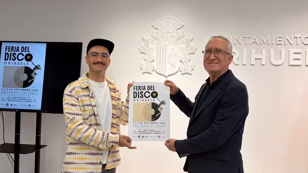 Dos hombres sostienen el cartel de la Feria del Disco ante el escudo municipal de Orihuela.