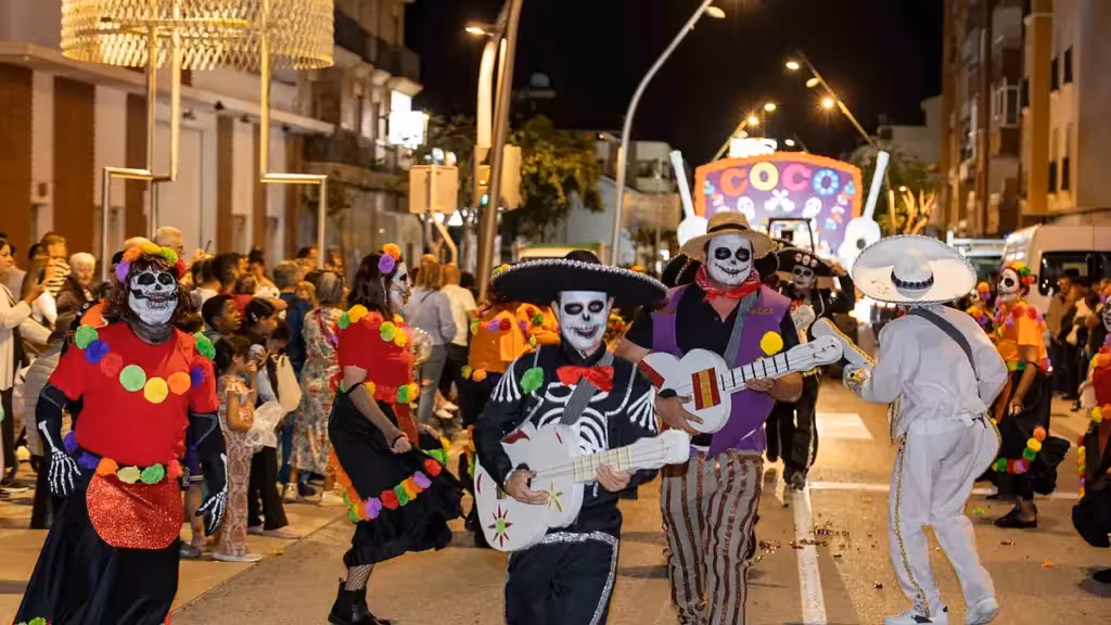Participantes con maquillaje de calavera y guitarras delante de la carroza Coco en Pilar de la Horadada