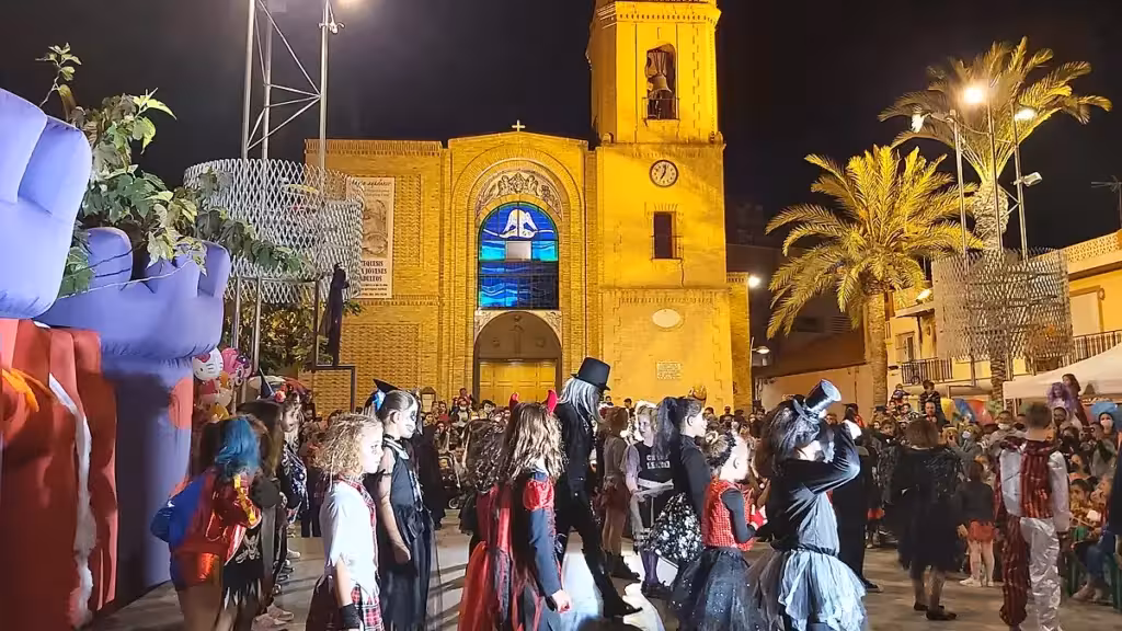 Imagen de archivo de participantes disfrazados ante una iglesia iluminada de noche en Pilar de la Horadada
