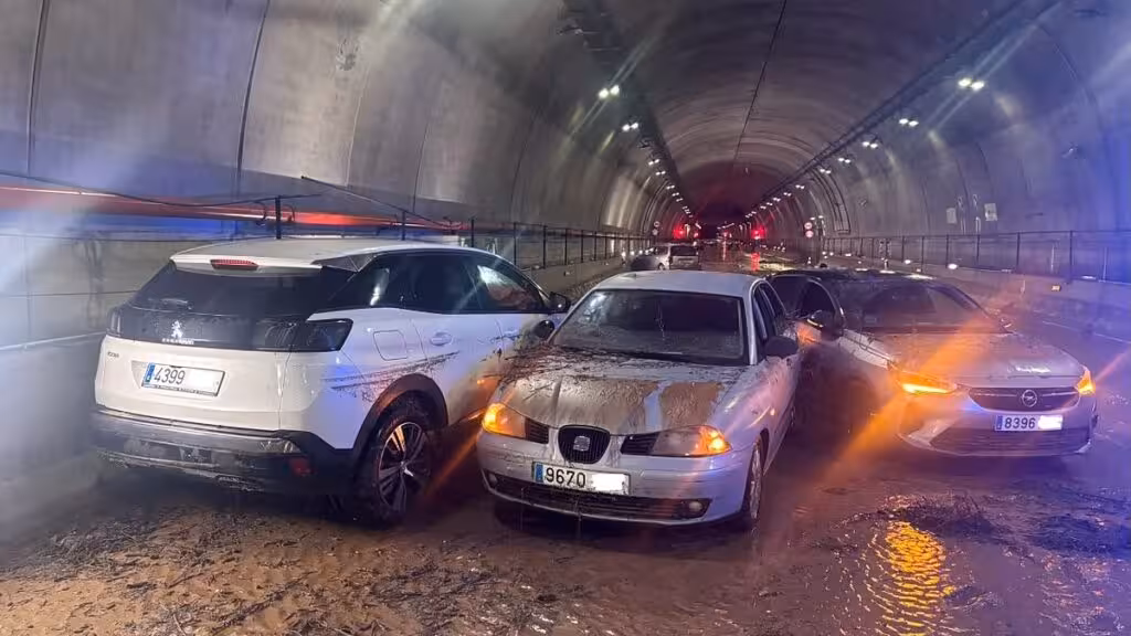 Mud-covered vehicles and water on the road inside an AP-7 tunnel in Pilar de la Horadada.