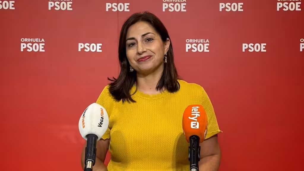 El PSOE pide a Orihuela un plan para ejecutar las dos campañas del Bono Consumo antes de fin de año Una mujer ante un atril con micrófonos y un fondo con los logotipos del PSOE de Orihuela.