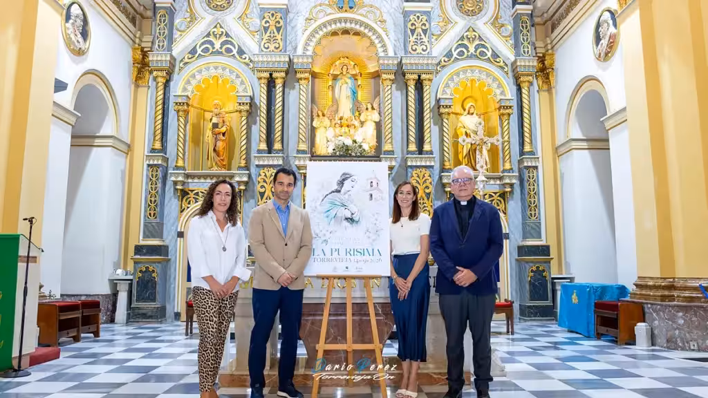 Cuatro personas junto al cartel de las fiestas de la Purísima 2026 en el interior de una iglesia