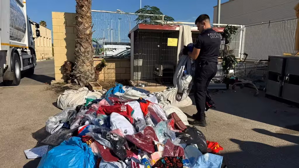 Un agente de la Policía Local junto a bolsas y prendas intervenidas