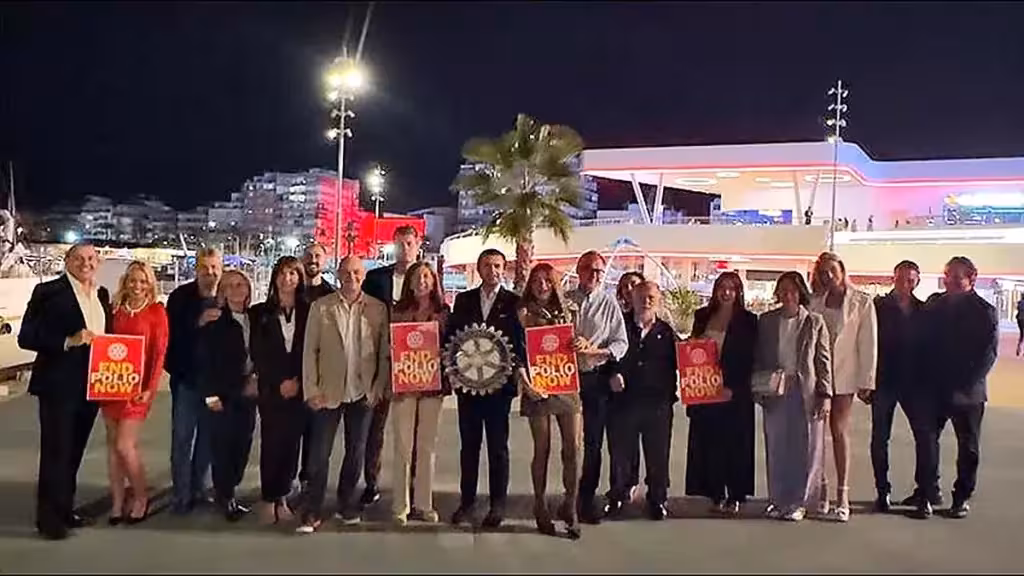 Participantes con carteles End Polio Now frente al Centro de Ocio Paseo del Mar iluminado de rojo