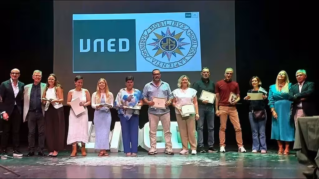 Participantes con diplomas en el escenario durante el acto académico de la UNED de Torrevieja