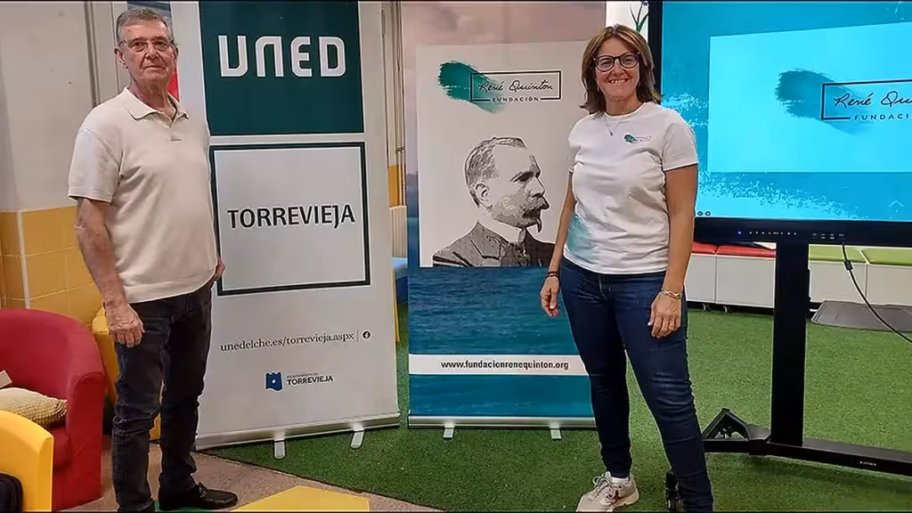 Dos personas junto a expositores de UNED Torrevieja y la Fundación René Quinton en un espacio educativo