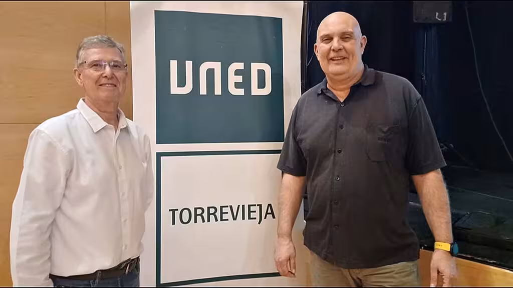 Two men beside a display bearing the name of UNED Torrevieja