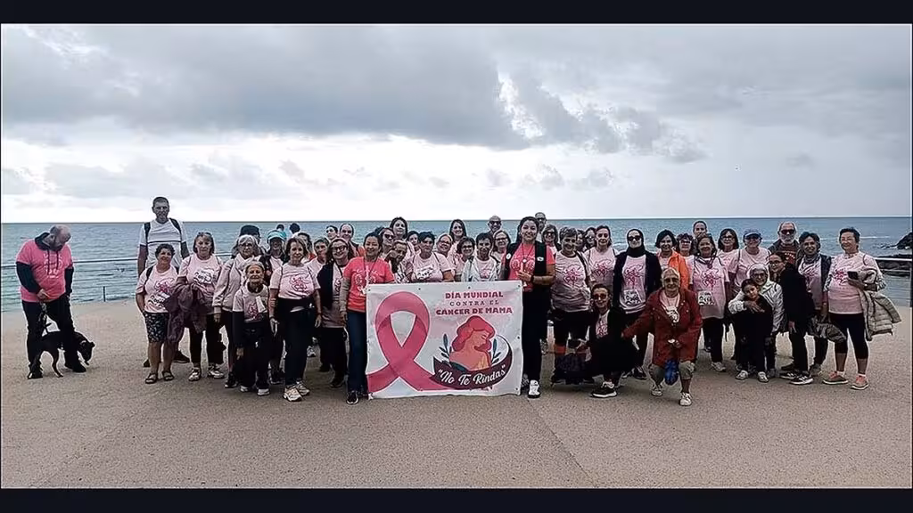 La XI Marcha contra el Cáncer de Mama recorre el litoral de Torrevieja pese a la lluvia Participantes de la marcha junto al mar con camisetas rosas y una pancarta de apoyo contra el cáncer de mama